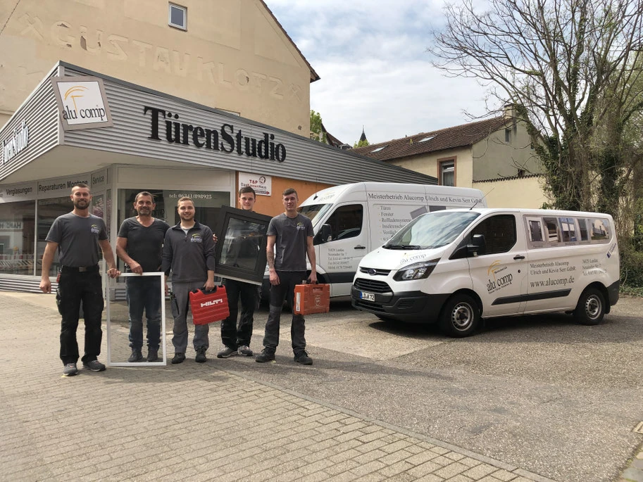 Team vor TürenStudio mit Fenstern, Werkzeug und Servicefahrzeugen draußen